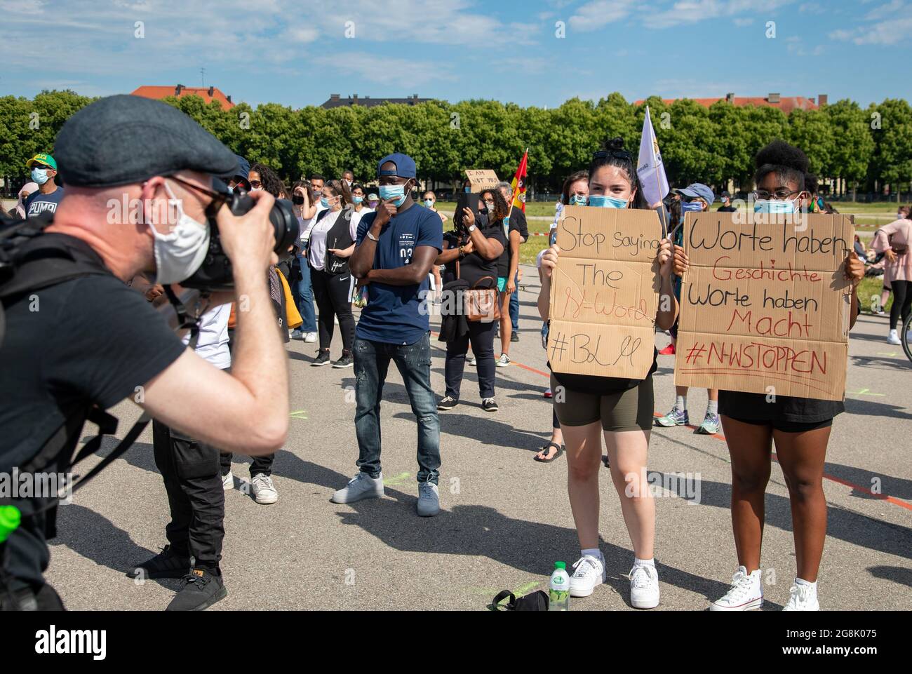 Fotograf schießt ein Bild Bild von zwei Aktivistinnen mit Schildern: " Stop  saying then-word # BLM ", " Worte haben Geschichte Worte haben Macht #  N-WStoppen ". Mehrere hundert Menschen haben sich