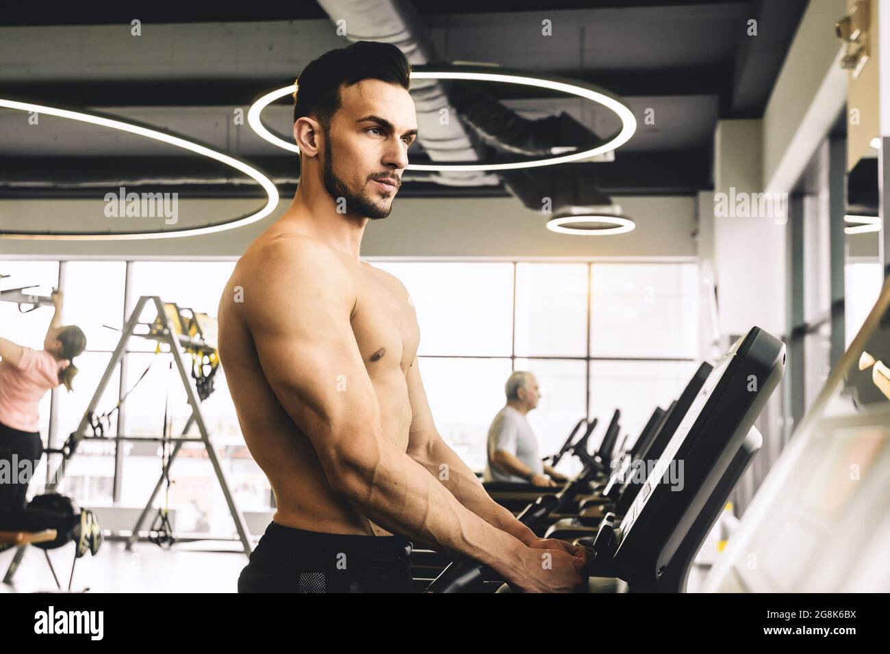 Handsome young sporty male bodybuilder with naked torso doing exercise