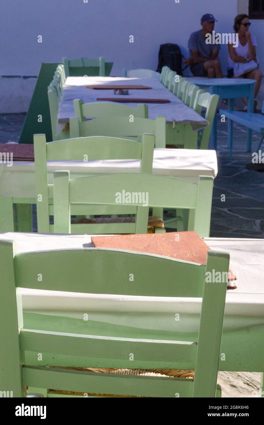 Folegandros island Greece Tables and chairs in a restaurant Close up selective focus view of traditional wooden Greek taverna furniture Blurred backgr Stock Photo