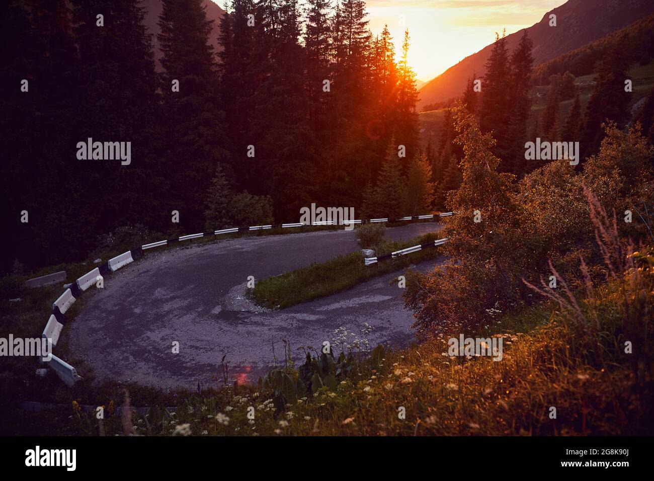 Asphalt road serpentine turn in the mountains in Kazakhstan at sunset sky. Famous mountain road to Big Almaty Lake. Stock Photo
