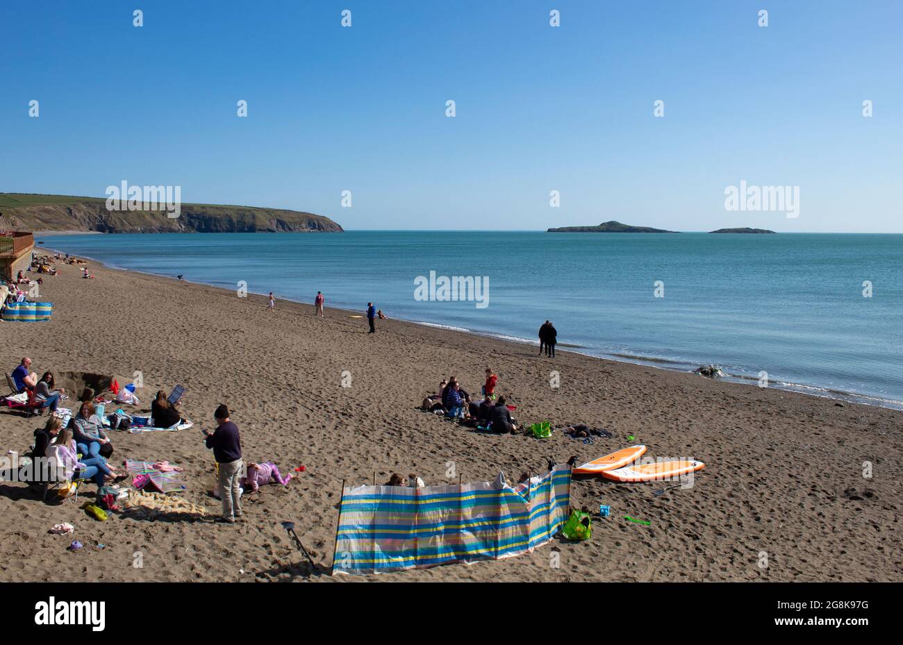 Aberdaron - Wales - April 3 2021 : Traditional seaside scene Holiday makers relax on a fine sandy beach under a clear blue sky Landscape aspect with c Stock Photo