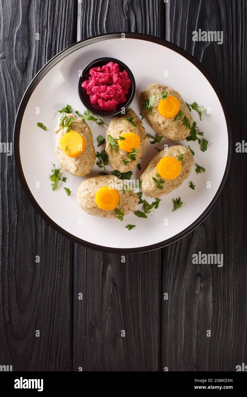 Classic Gefilte Fish Gently cooked fish patties in the simmering fish stock closeup in the plate on the tble. Vertical top view from above Stock Photo