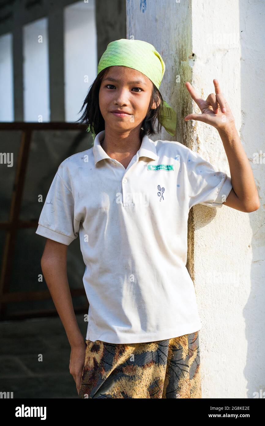 Young Burmese boy wearing bandana giving cool rocker hand gesture poses for photo, Shwezigon Paya Temple, Bagan, Myanmar Stock Photo