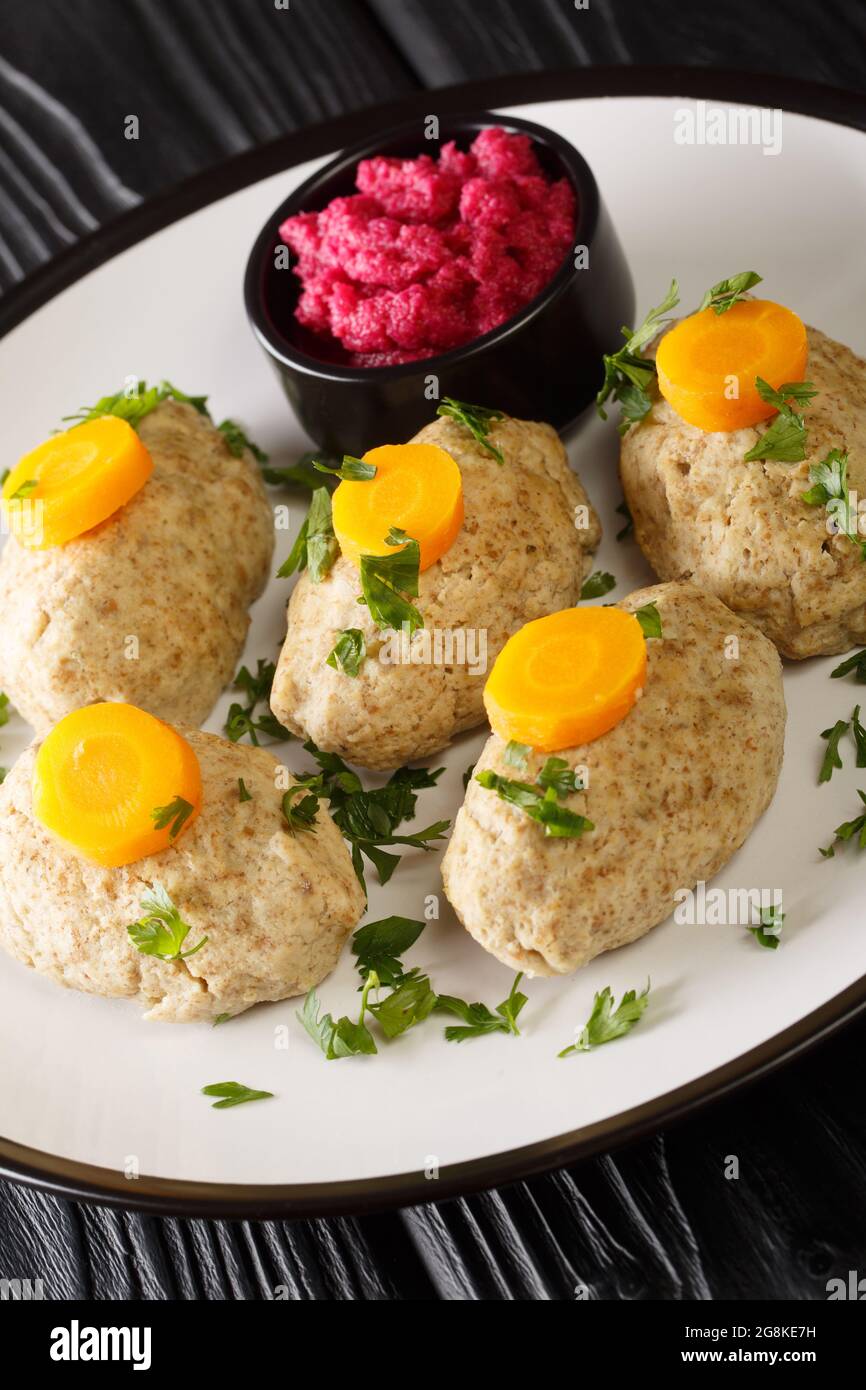 Classic Gefilte Fish Gently cooked fish patties in the simmering fish stock closeup in the plate on the tble. Vertical Stock Photo