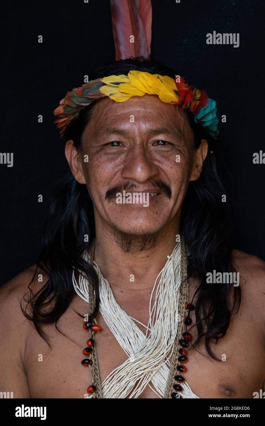 A man displays his colourful headdress and jewellery. AMAZONIAN ECUADOR: In one image, a woman wore red makeup across her eyes and a feathered headdre Stock Photo