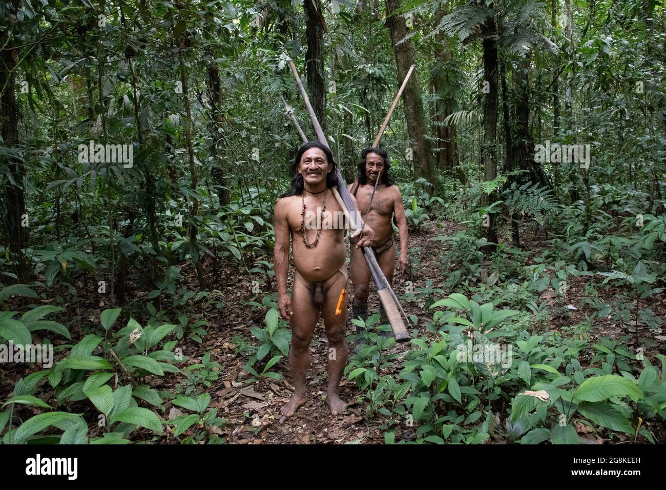 A hunting expedition made its way into the jungle. AMAZONIAN ECUADOR: In one image, a woman wore red makeup across her eyes and a feathered headdress Stock Photo