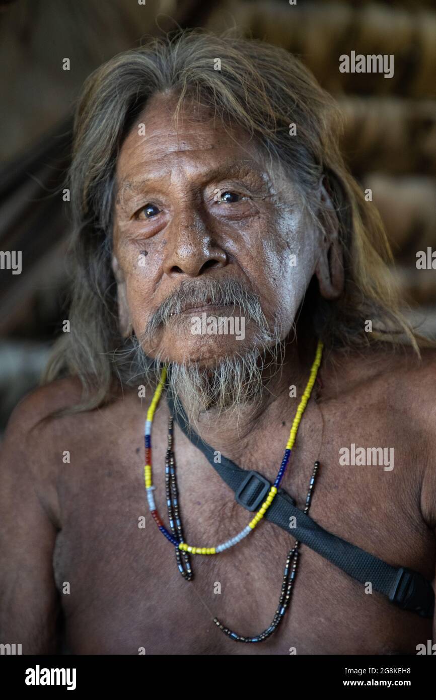 An elder male with large stretched earlobes looked into the camera. AMAZONIAN ECUADOR: In one image, a woman wore red makeup across her eyes and a fea Stock Photo