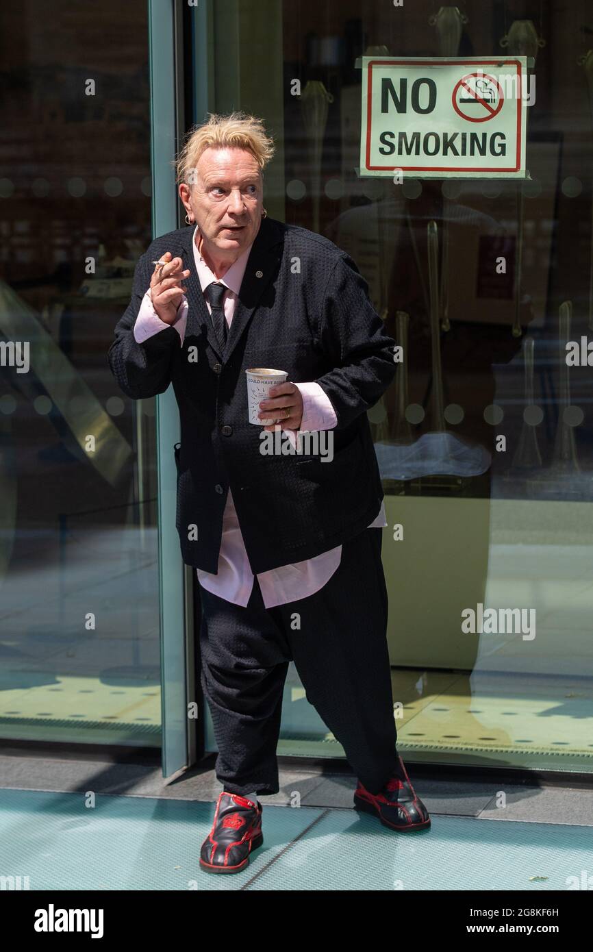 John Lydon, aka Johnny Rotten, smokes outside the Rolls Building at the High Court, London, where he is giving evidence in a hearing between two former Sex Pistols band members and the frontman over the use of their songs in a television series. Picture date: Wednesday July 21, 2021. Stock Photo
