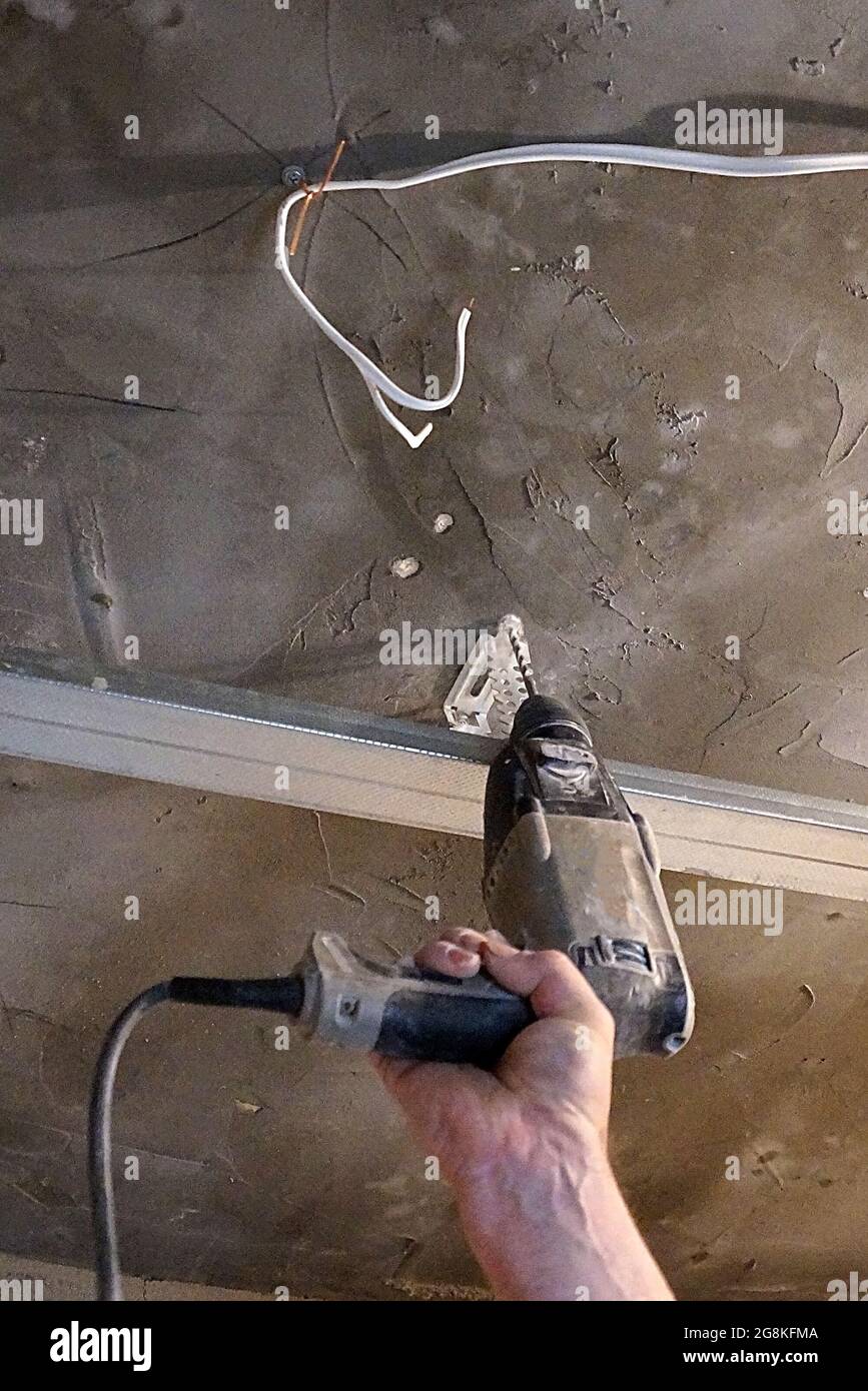 male hand with screwdriver fastening profile for suspended plasterboard ceiling close-up Stock Photo