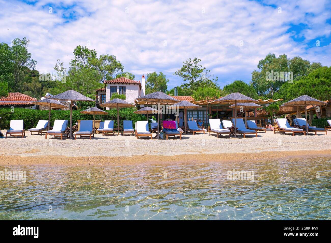 SKIATHOS, GREECE - Jun 17, 2021: A few holidaymakers enjoying the sun, sea, and sand on Kolios beach Stock Photo