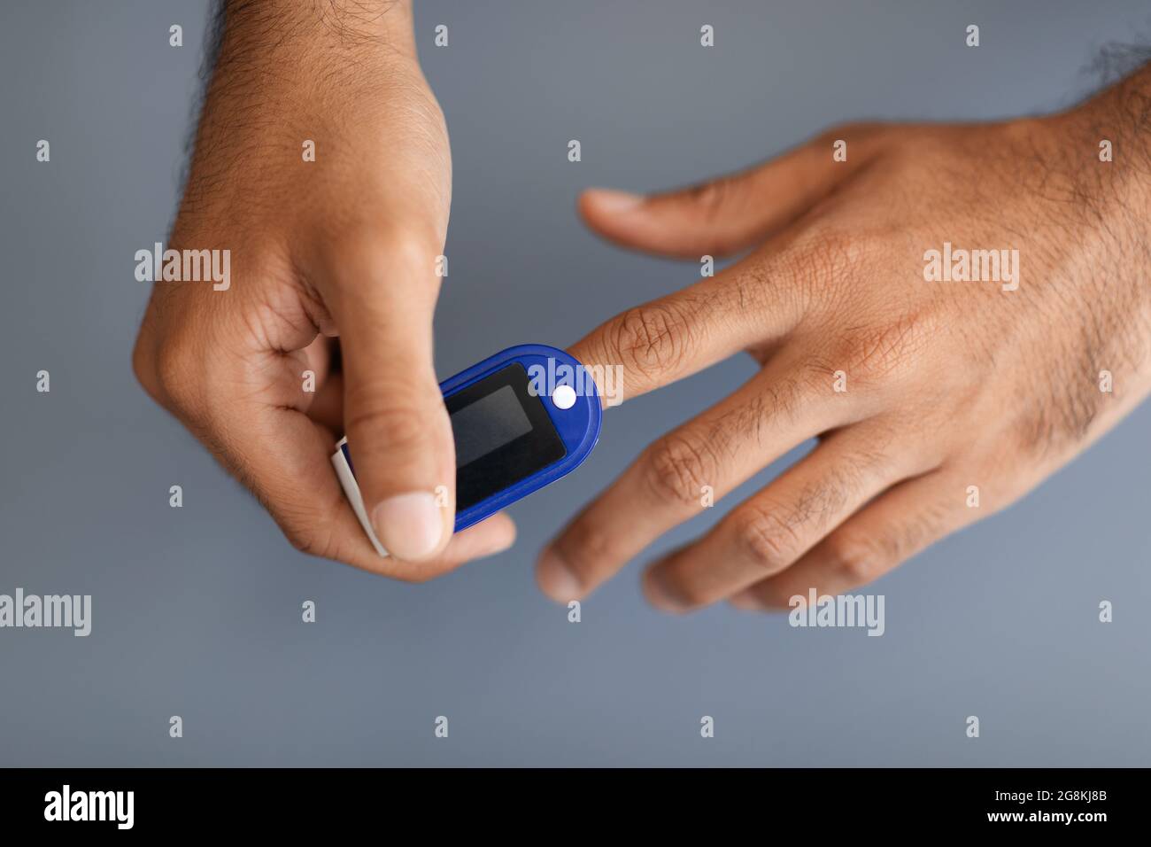 Unrecognizable man using pulse oximeter, grey background Stock Photo