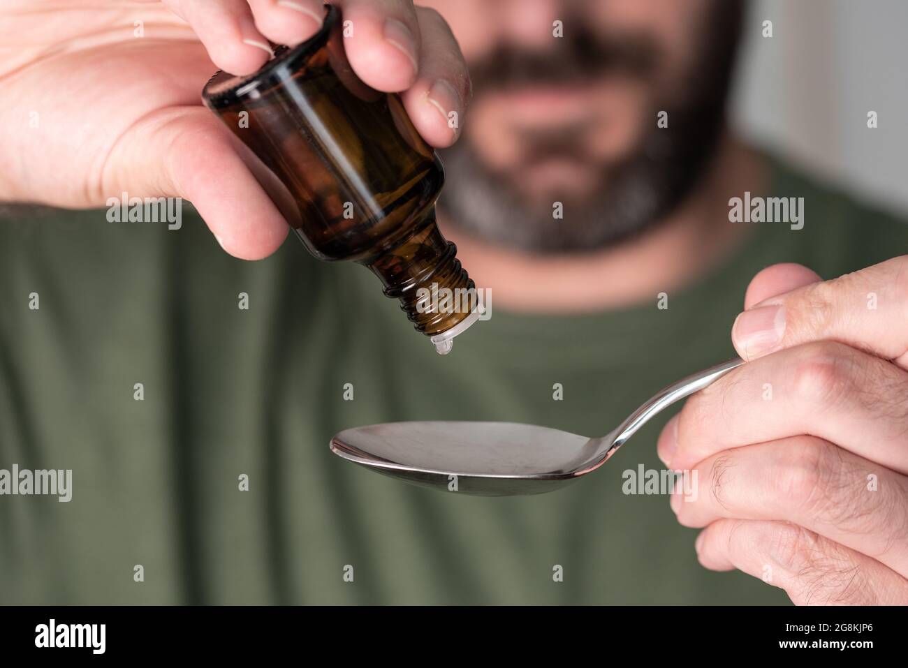 close-up of person dripping liquid medication drops onto spoon Stock Photo