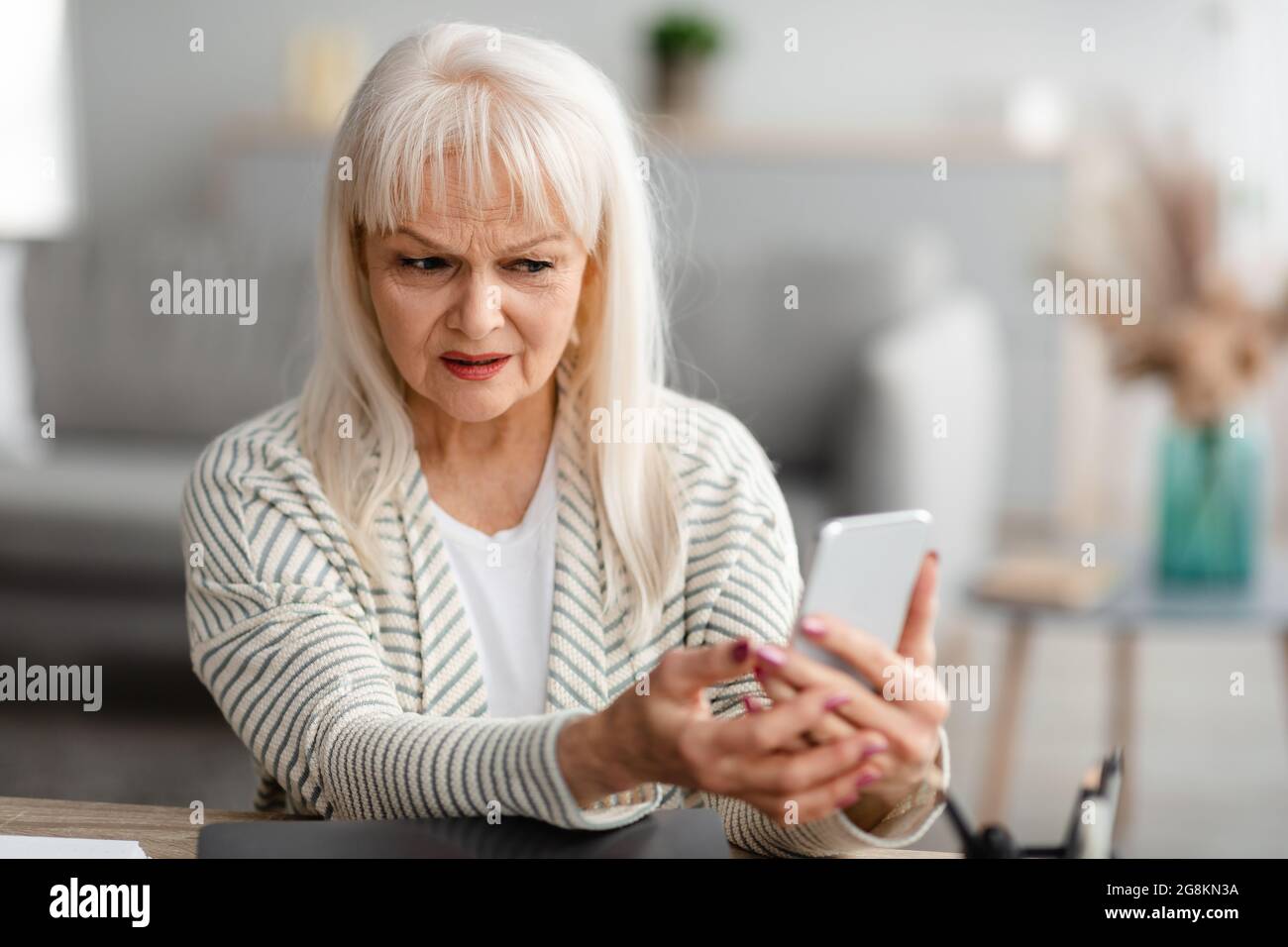 Confused senior woman using her mobile phone Stock Photo