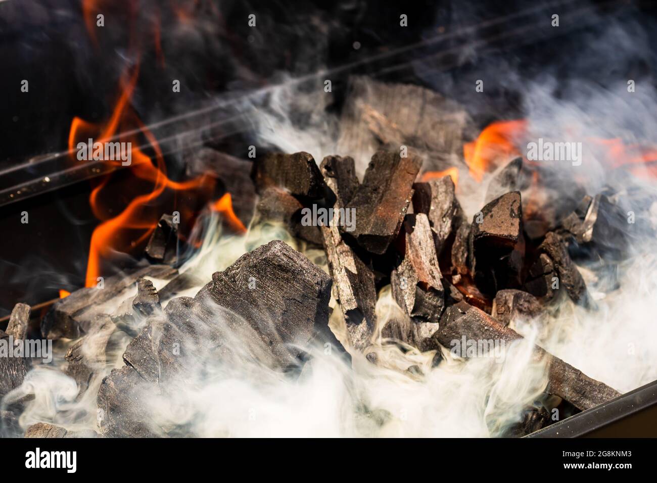 Barbecue grill pit with glowing and flaming hot charcoal briquettes