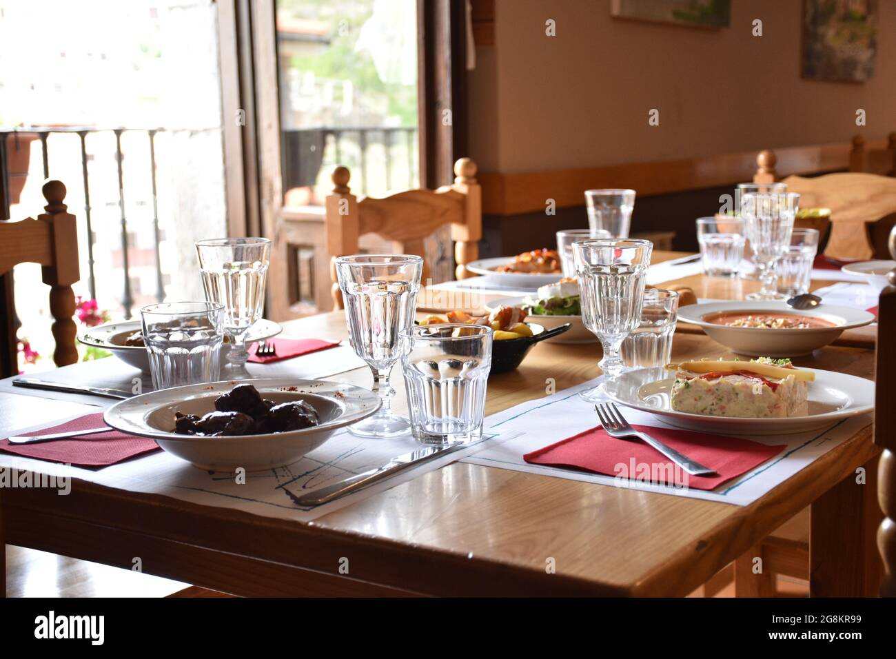 Restaurant table with plates full of food in rural area restaurant. Everything ready to eat and with lots of light coming through the window. Stock Photo