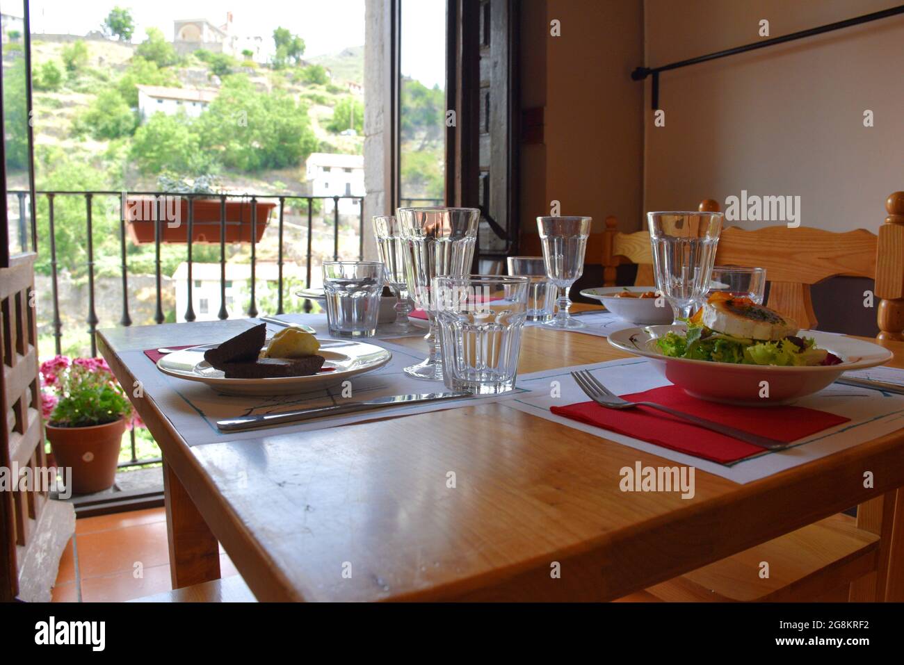 Restaurant table with dishes from the daily menu ready to be tasted. Located next to sale and overlooking a rural mountain area. Stock Photo