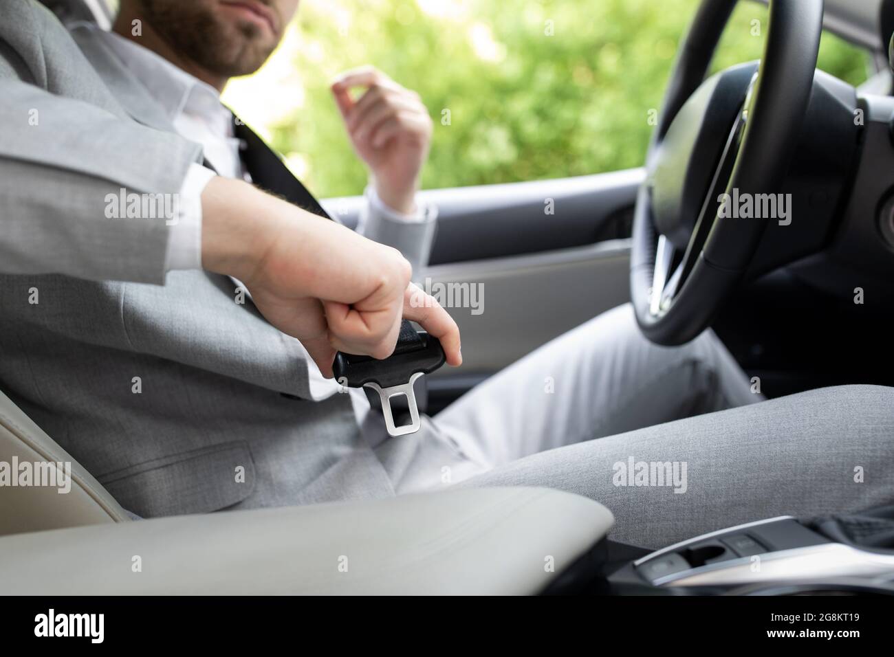 Male hand fastens seat belt in car. Buckle seat belt while sitting inside car before driving Stock Photo
