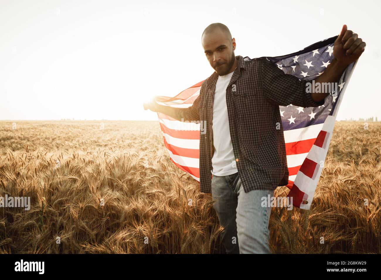 African american young man holding USA national flag through wheat ...