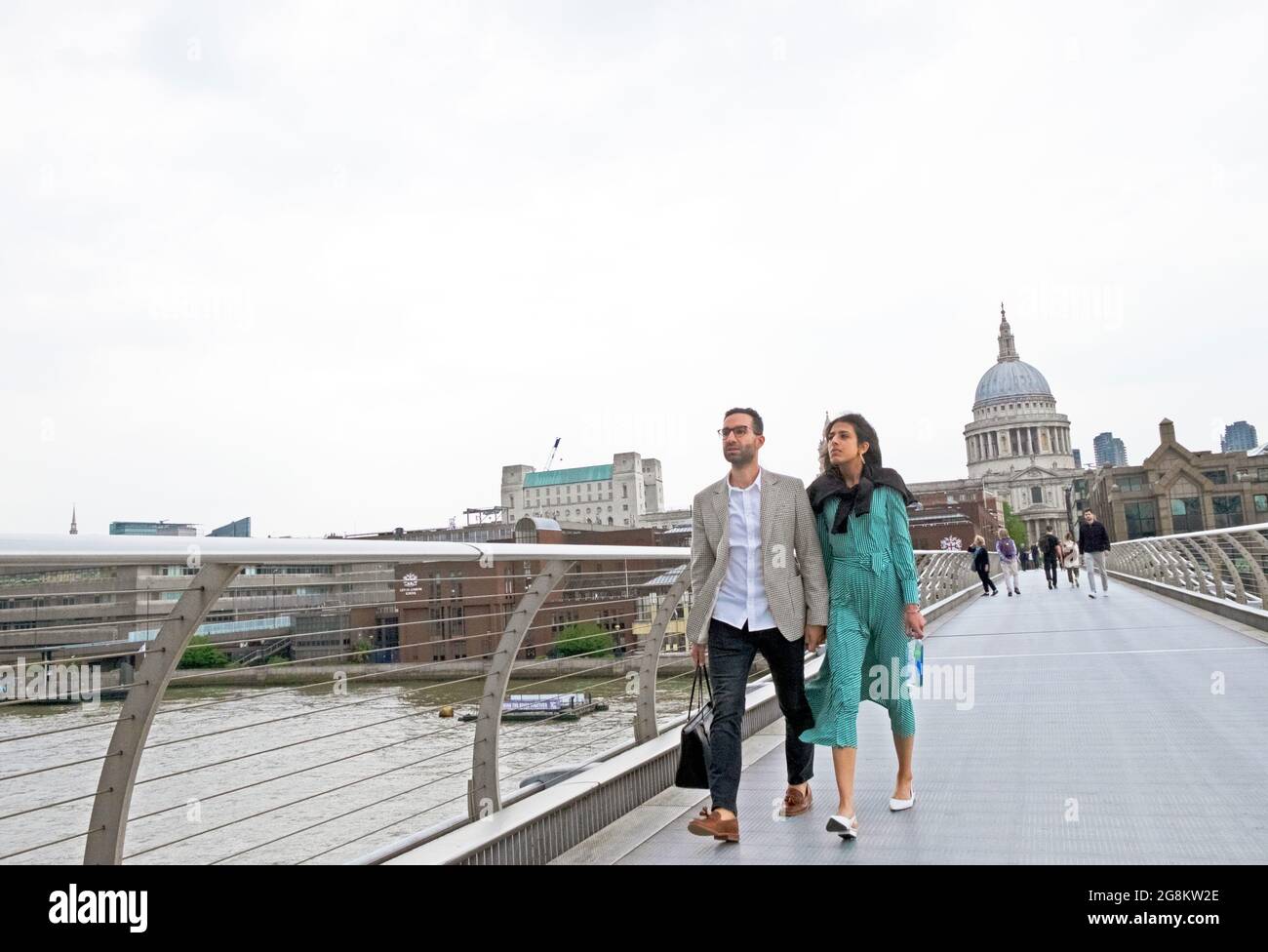 Asian couple holding hands walking on the Millennium Bridge towards the Tate Modern art gallery in summer 2021 during Covid London UK  KATHY DEWITT Stock Photo