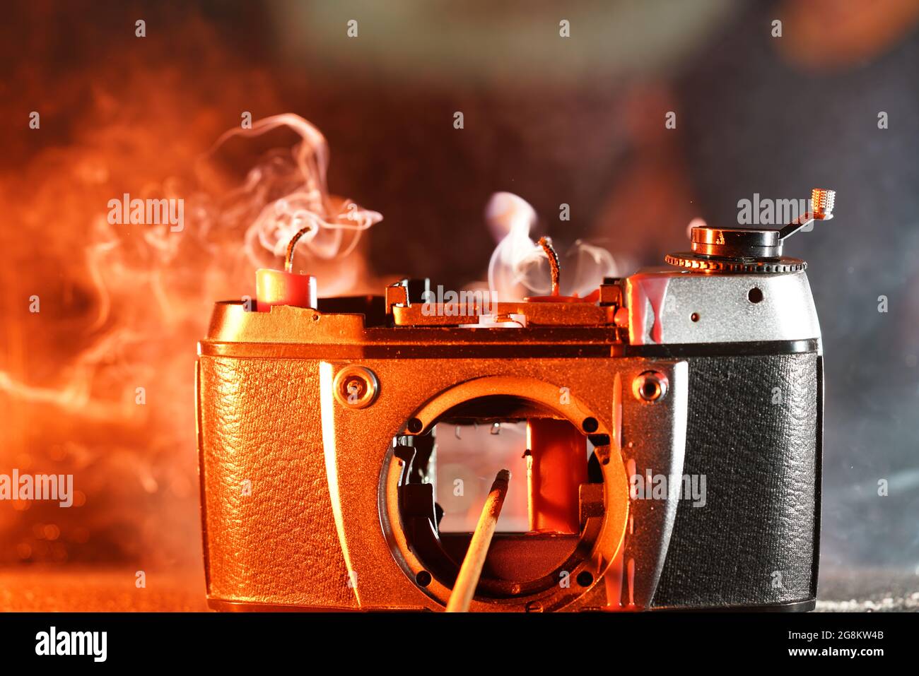 Closeup shot of an old, broken, burning camera with red candles inside ...