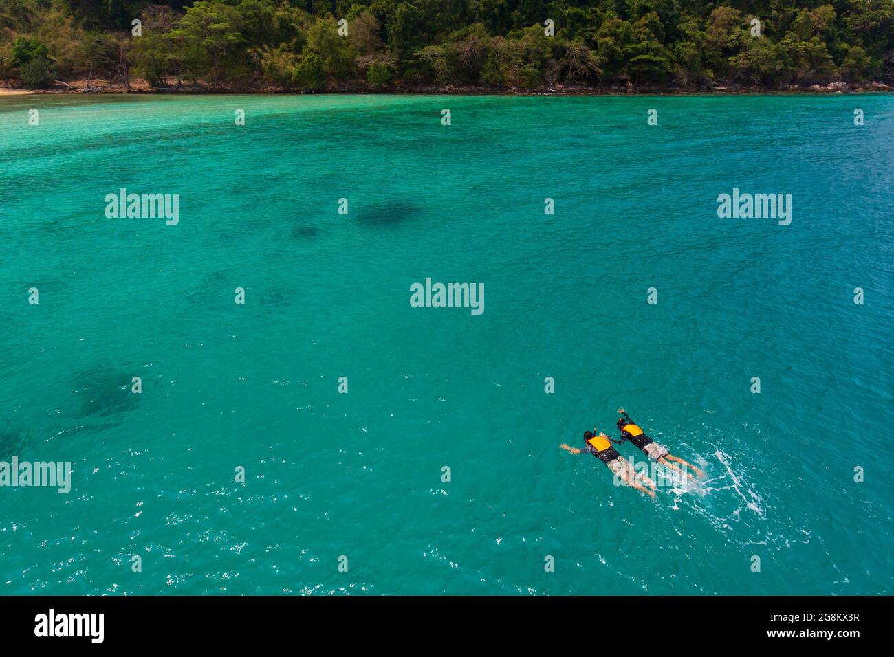 Couple catch each other hands and swim, skin diving to sea reef in