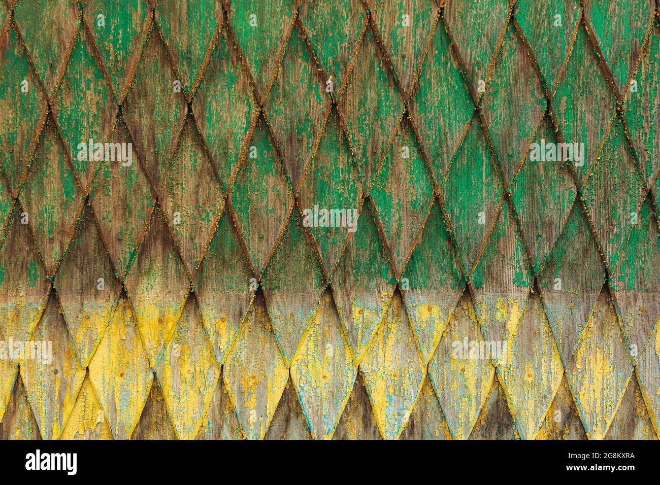 Ornamental covering on the house wall. Grunge yellow and green colored wooden coating texture Stock Photo