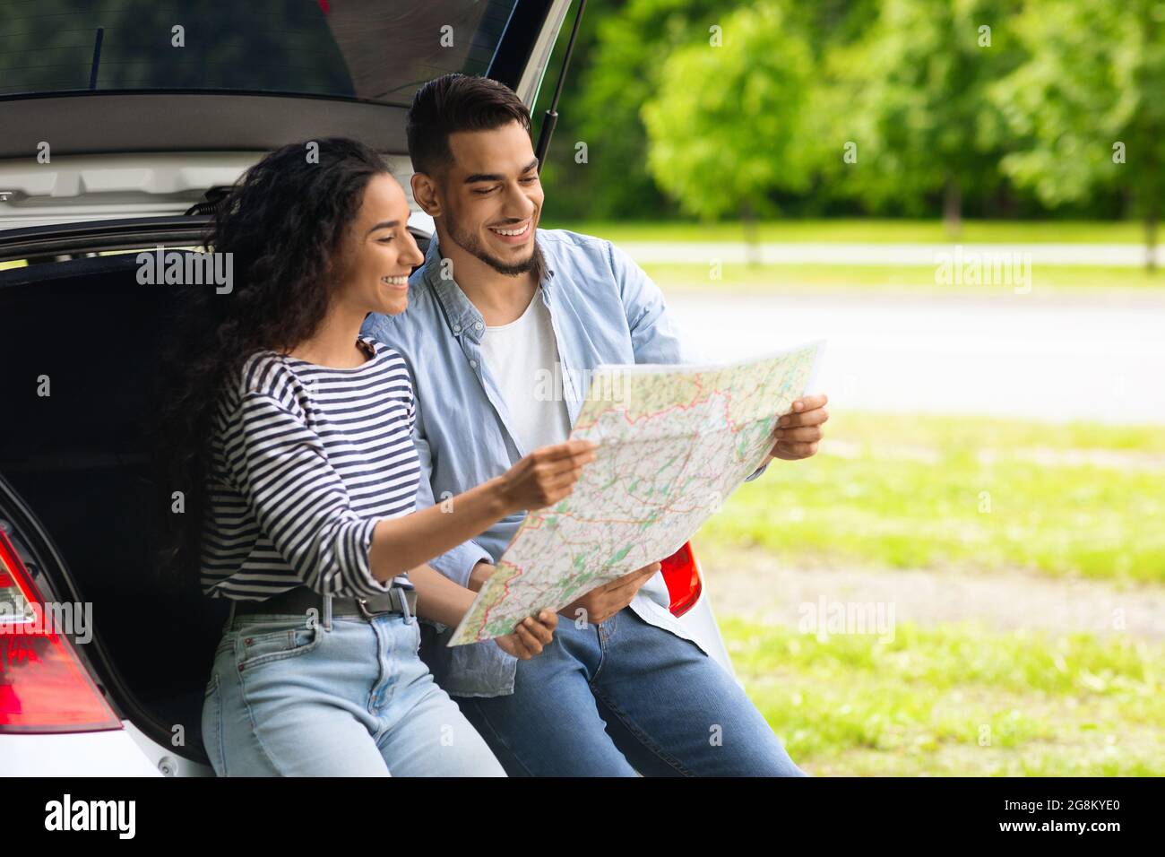 Loving middle-eastern couple watching map while having break, copy space Stock Photo