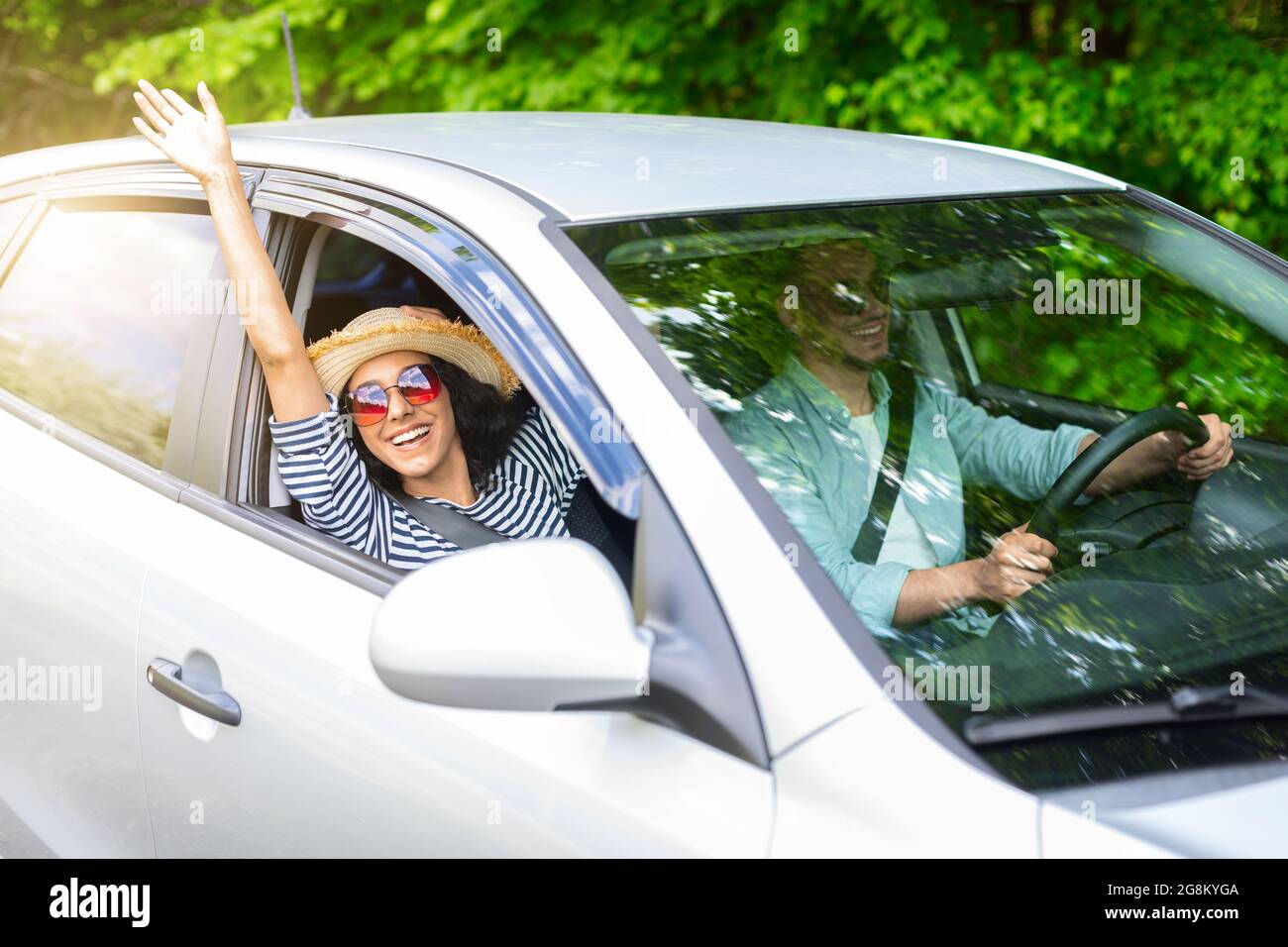 Excited young lady enjoying car trip with her boyfriend Stock Photo