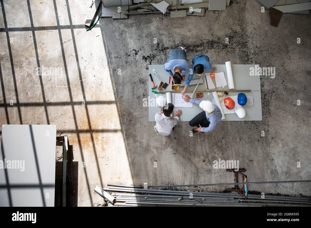 Four persons team of engineers talk together to review constuction material and brainstorm about details of project Stock Photo