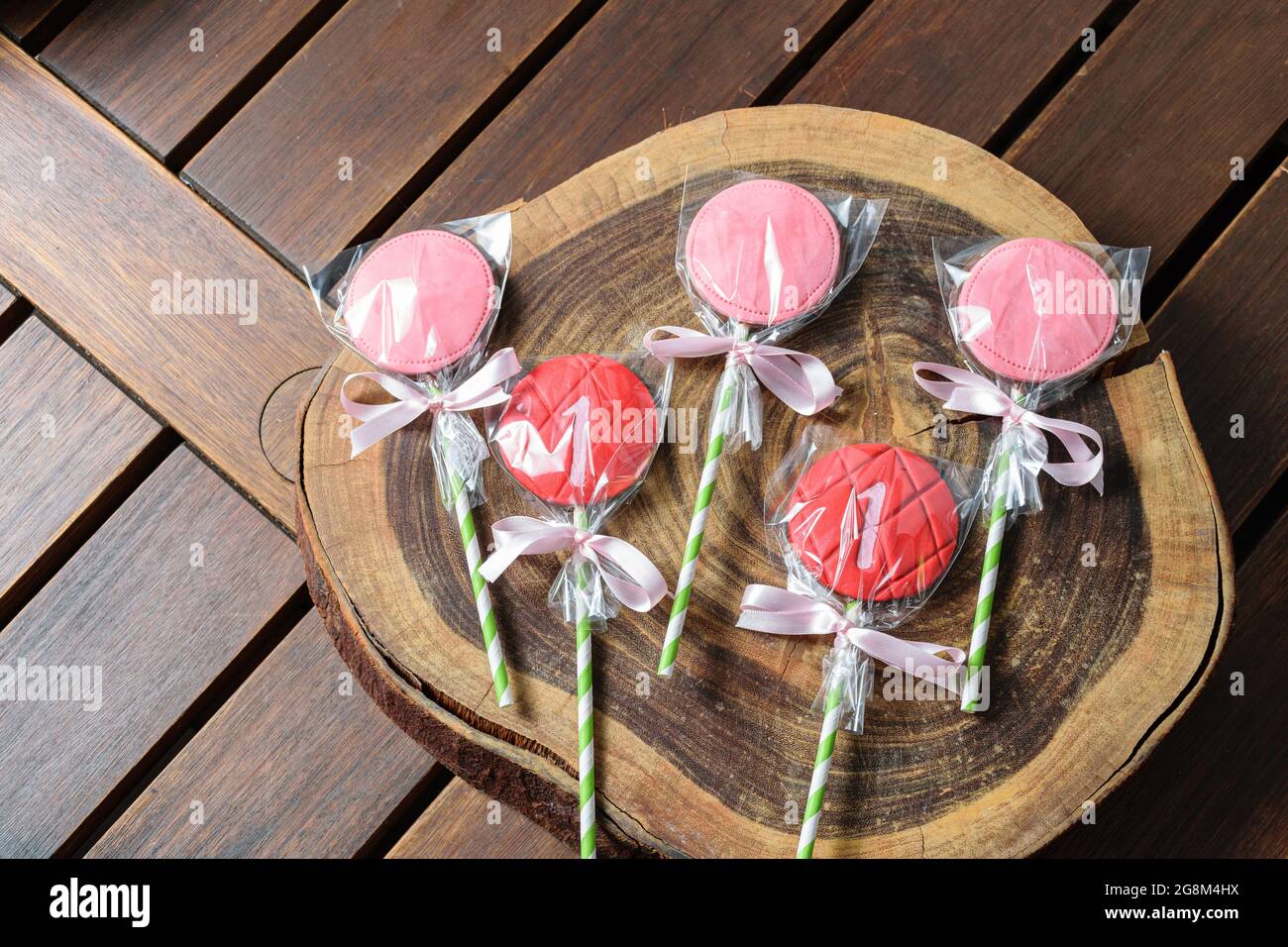 Strawberry flavored chocolate lollipops on a wooden log board. Stock Photo
