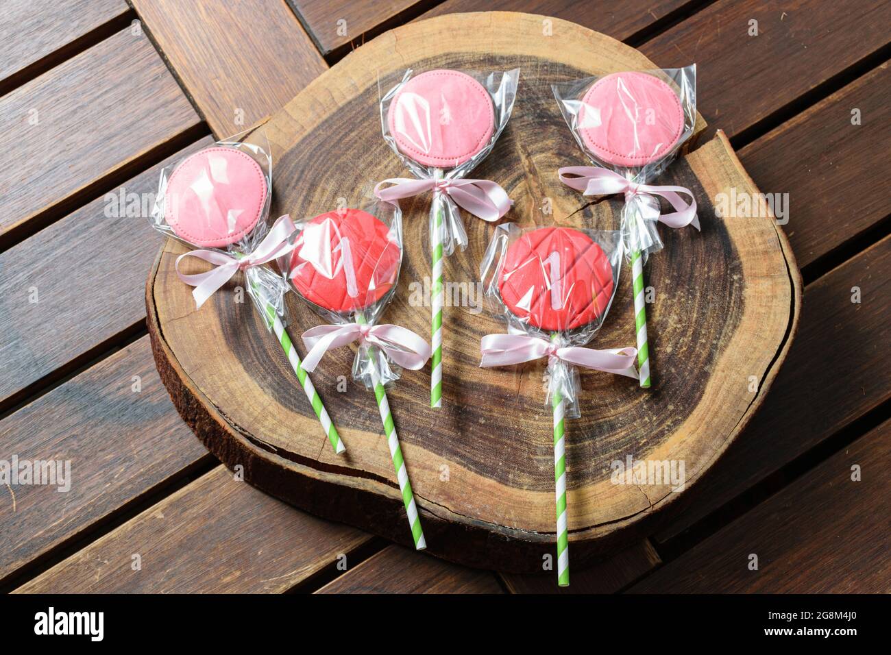 5 strawberry chocolate lollipops on a wooden log board. Stock Photo