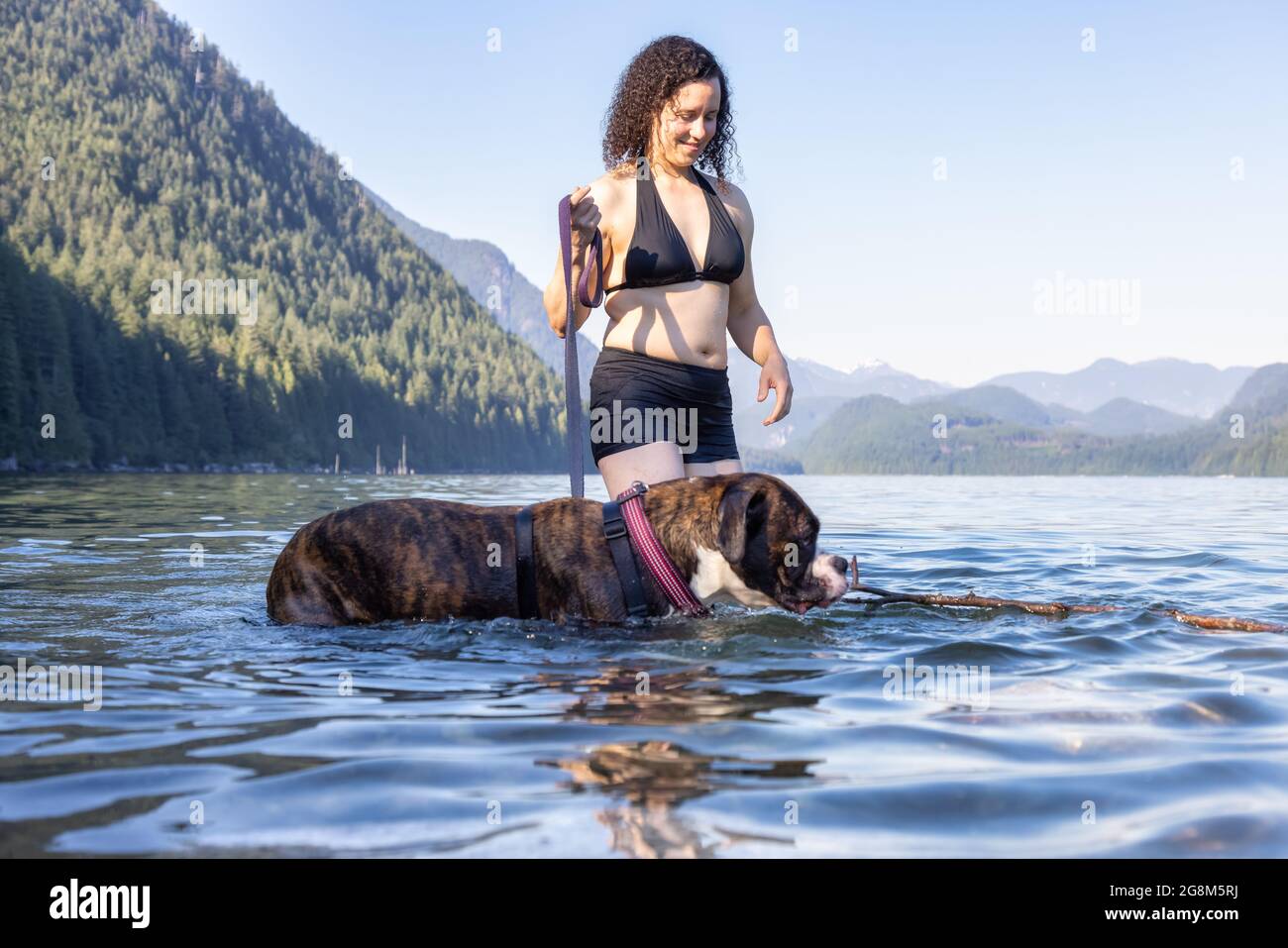 Caucasian Woman swimming in a lake with dog Stock Photo