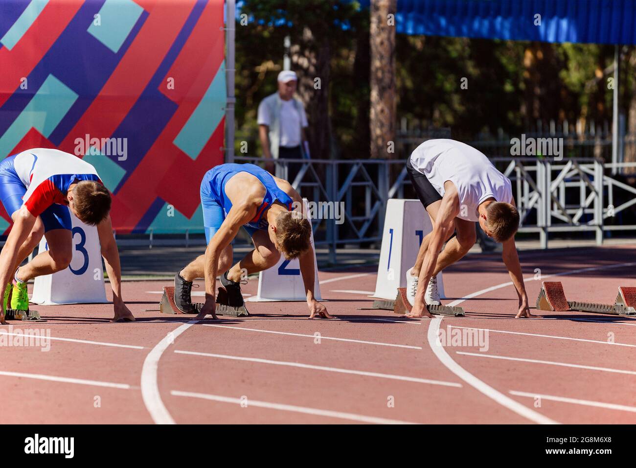 male athletes at starting positions of track and field race Stock Photo