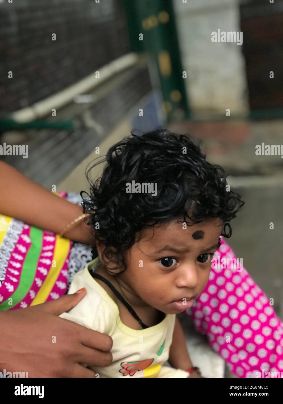 Indian baby boy with black curling hair with his baby sitter Stock Photo