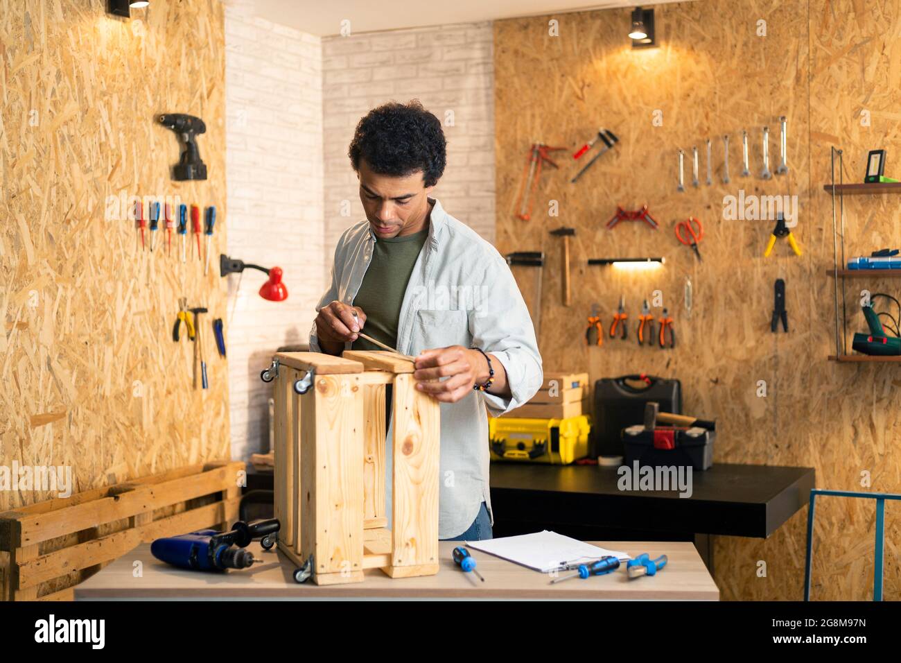 Carpenter measuring a wooden box and looking at his working drawings in workshop Stock Photo