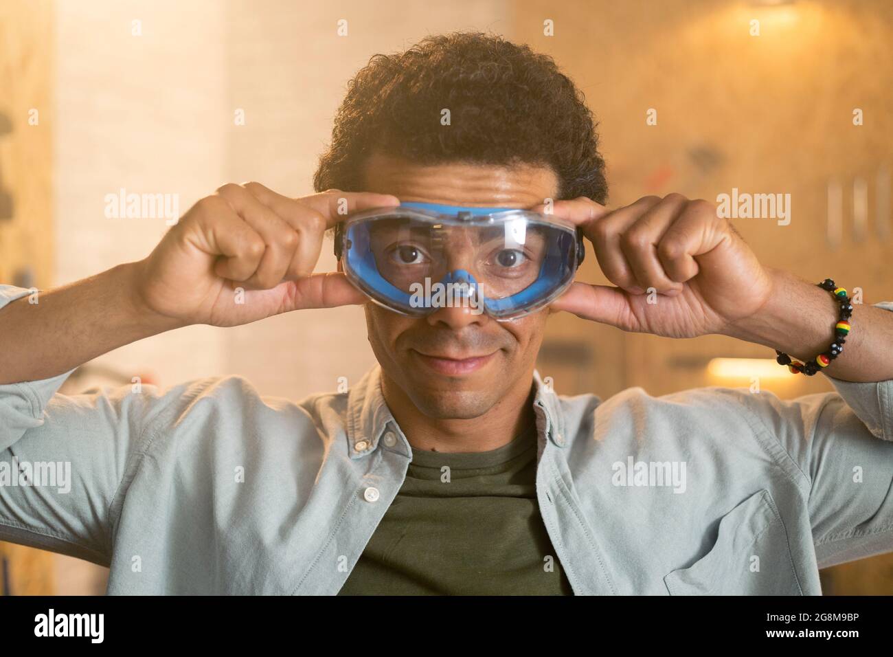 Portrait of a carpenter putting on safety goggles over his head in his  workshop Stock Photo - Alamy