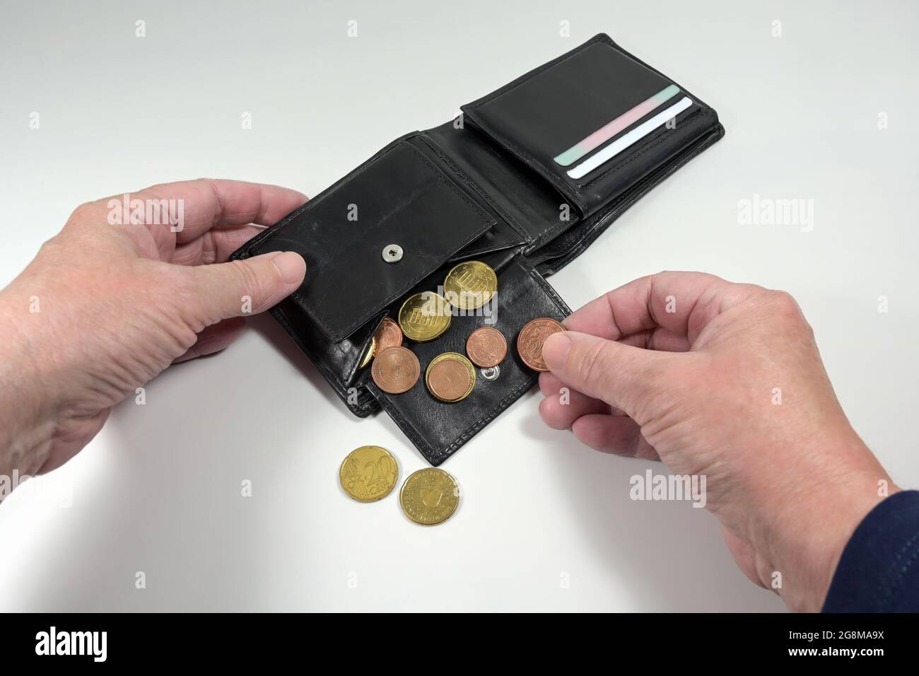 Hands taking the few euro coins out of a wallet, money concept for poverty and financial crisis during coronavirus pandemic, light gray background, se Stock Photo