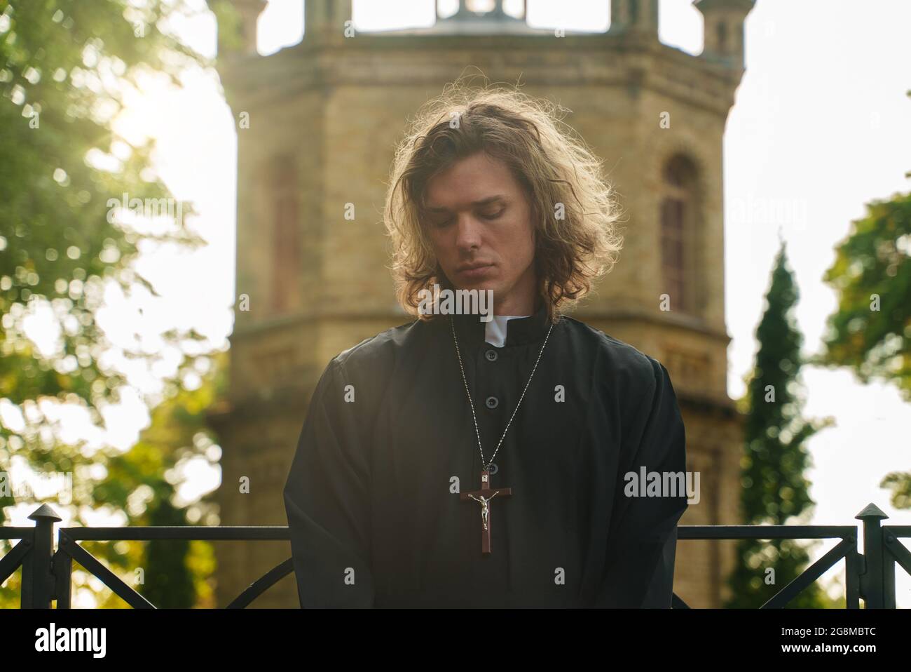 Christian priest with cross standing by the church. Stock Photo