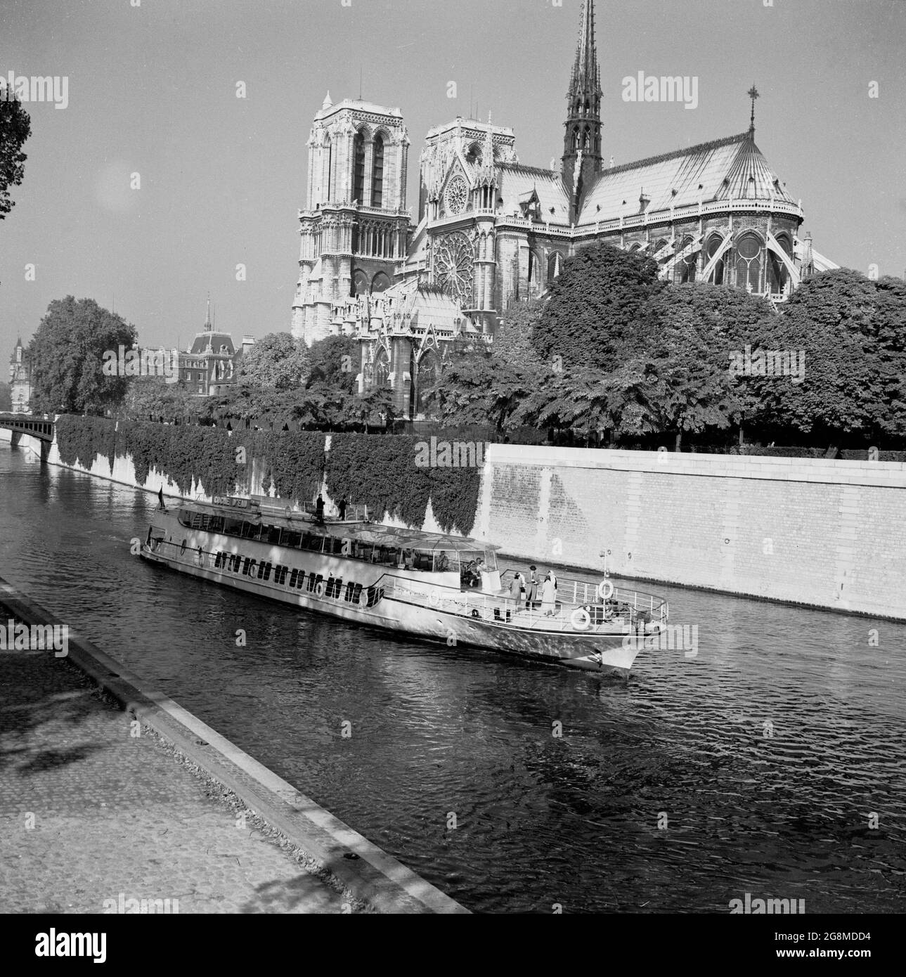 1950s, historical, a sightseeing pleasure cruise boat travelling on the river Seine going past the famous Notre-Dame Cathederal, Paris, France, A medieval Catholic church on the IIe de la Cite in the 4th arrondissement ofthe city, it is considered one of the finest examples of French Gothic architecture. Stock Photo