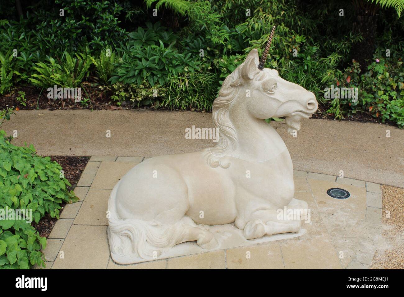 Unicorn sitting in on path of a garden Stock Photo