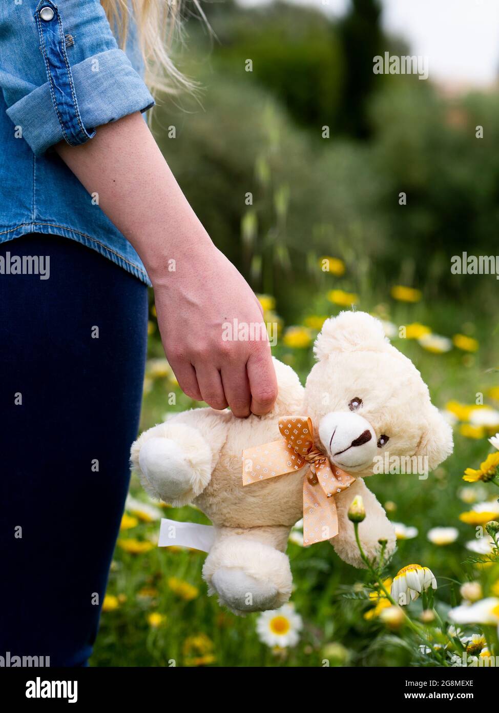Book cover concept - Childhood / Motherhood - Woman carrying teddy bear outdoors in nature Stock Photo