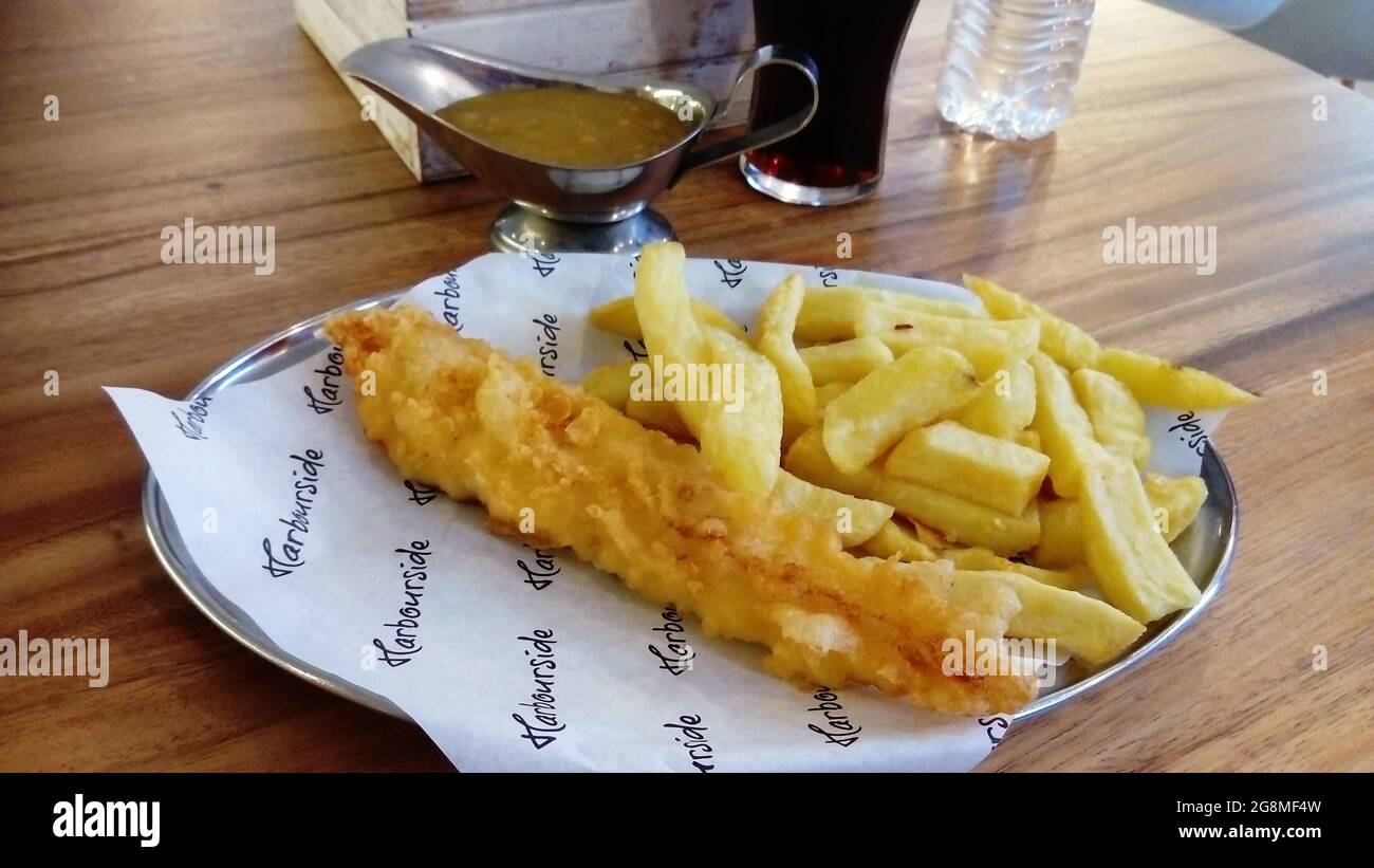 fish and chips on a platter with gravy dish Stock Photo