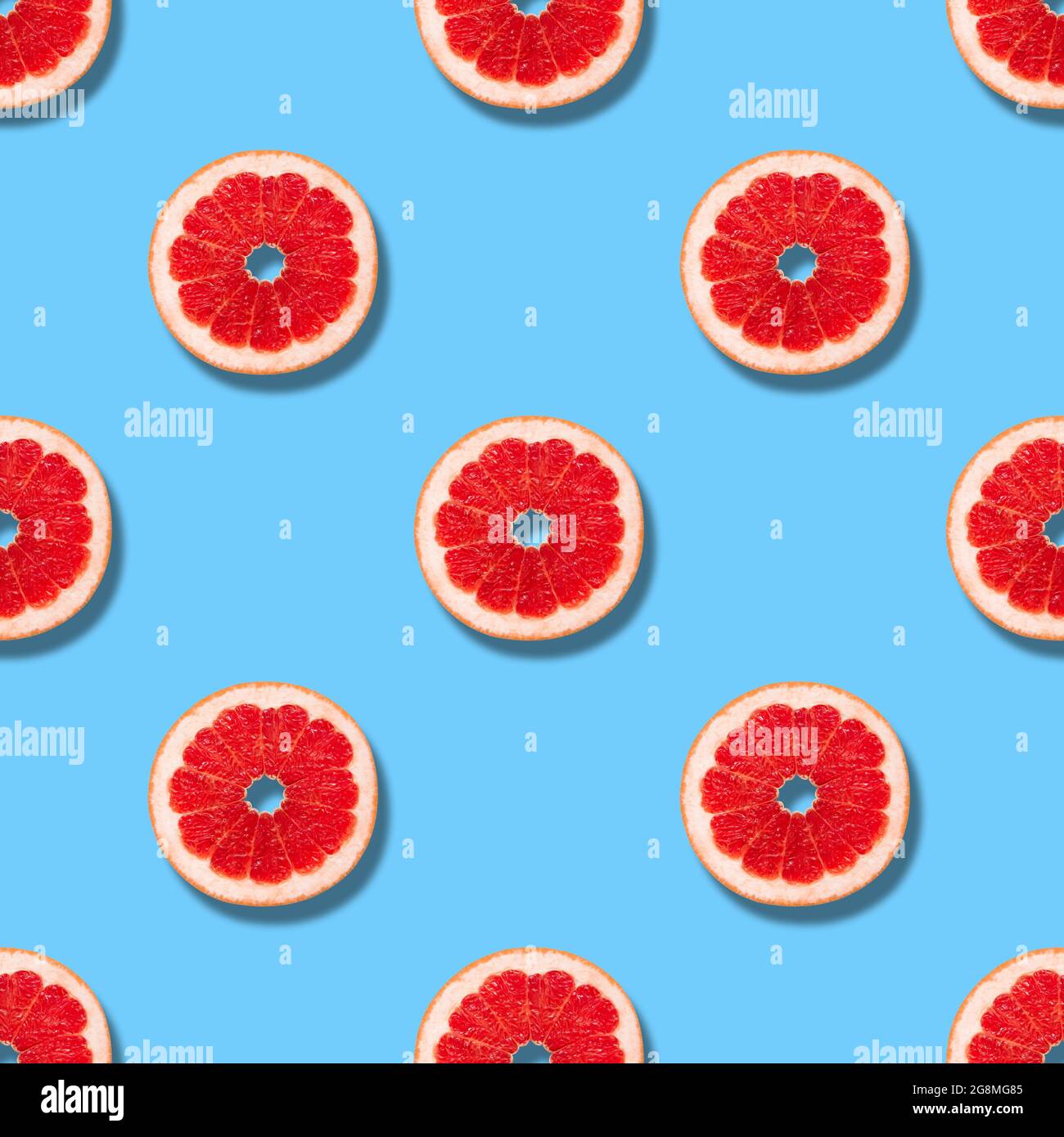 Seamless pattern with grapefruit on a blue background. Grapefruit slices seamless texture for design. Summer background. Fruit pattern. Stock Photo