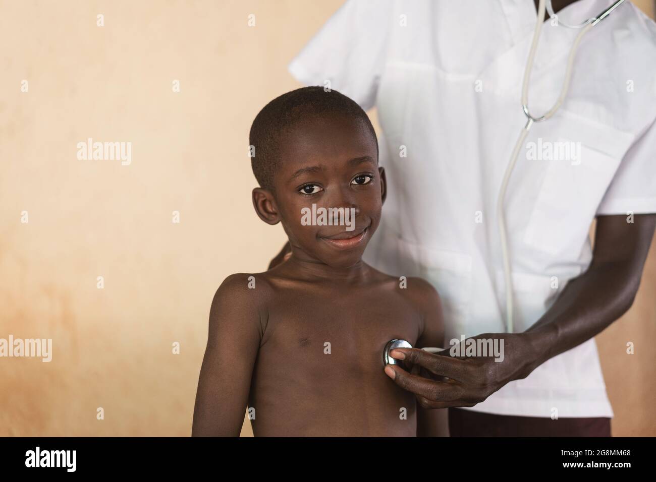 Horizontal photograph of African doctor home care for little African black boy. Health issues in Africa are unfortunately on the rise. Stock Photo