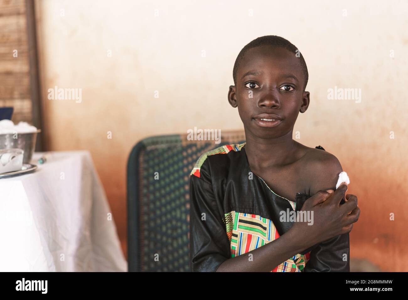 In this imagine a relieved and content looking African boys holds a cotton ball on the injection site after having receiving a routinary vaccination t Stock Photo