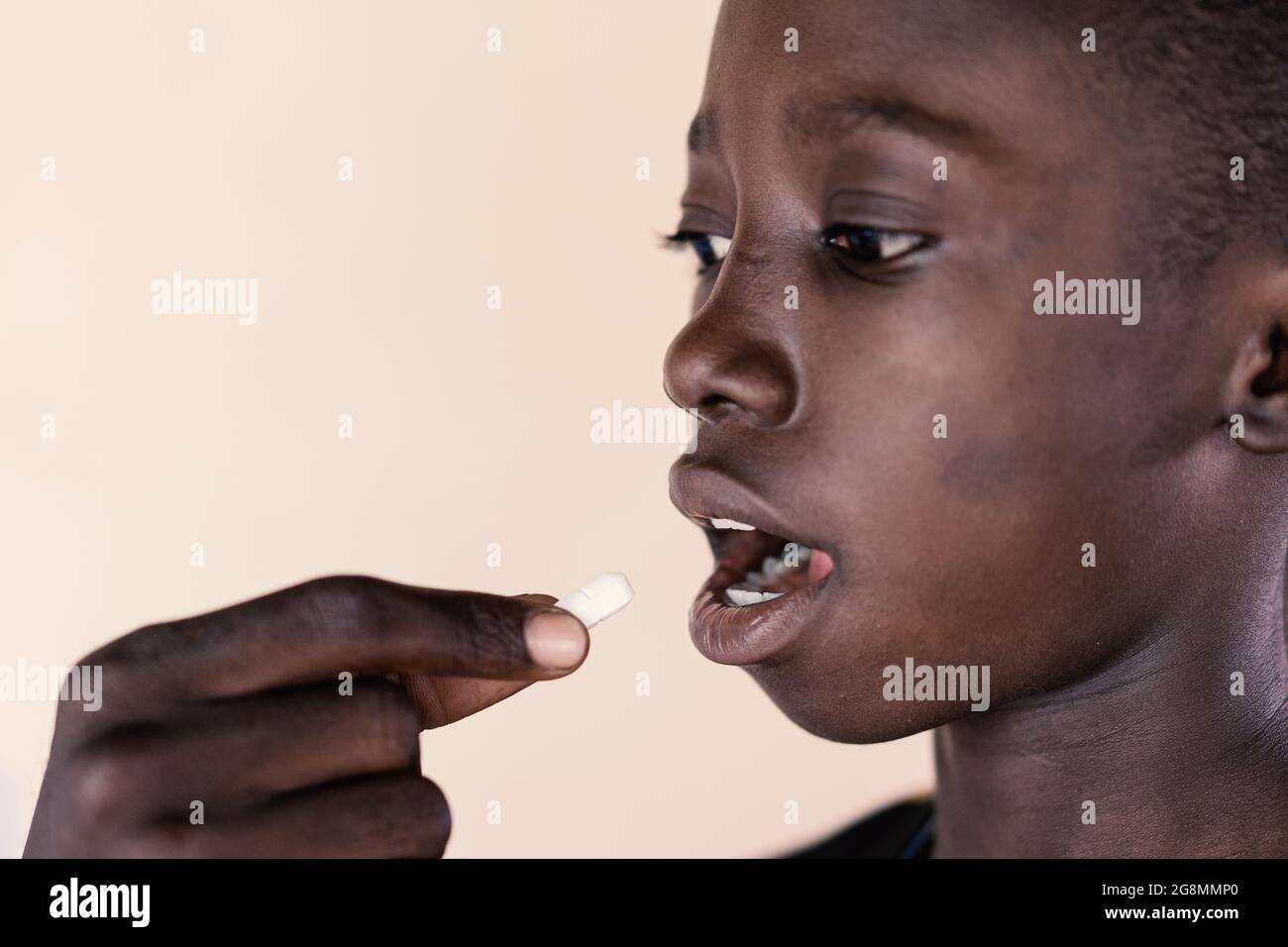 In this very close up shot, a young African boy given an oral medication. Concept image of medical drugs to prevent or cure a worldwide disease. Stock Photo
