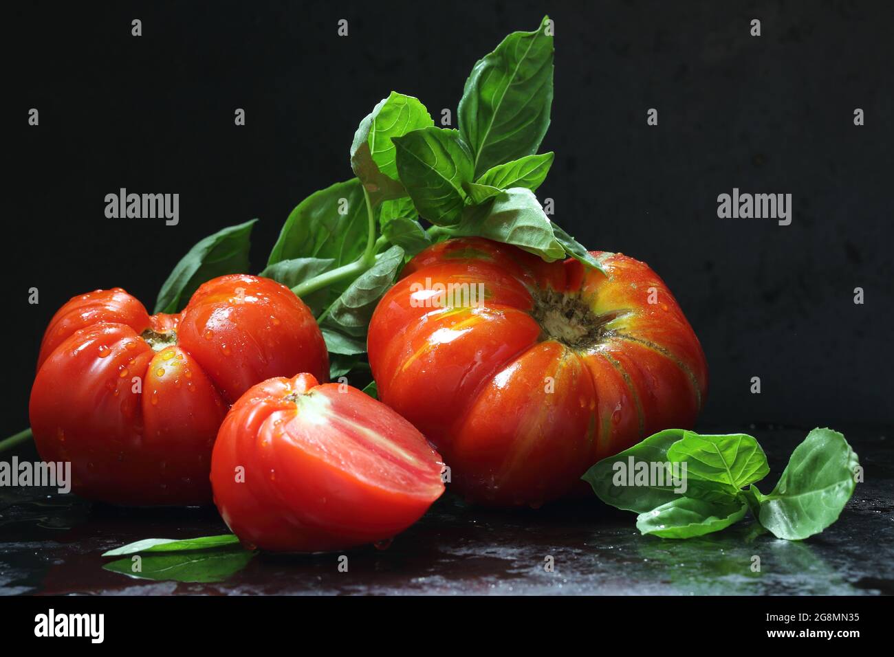 Still life with tomatoes, tomato juice and basil on a black background ...