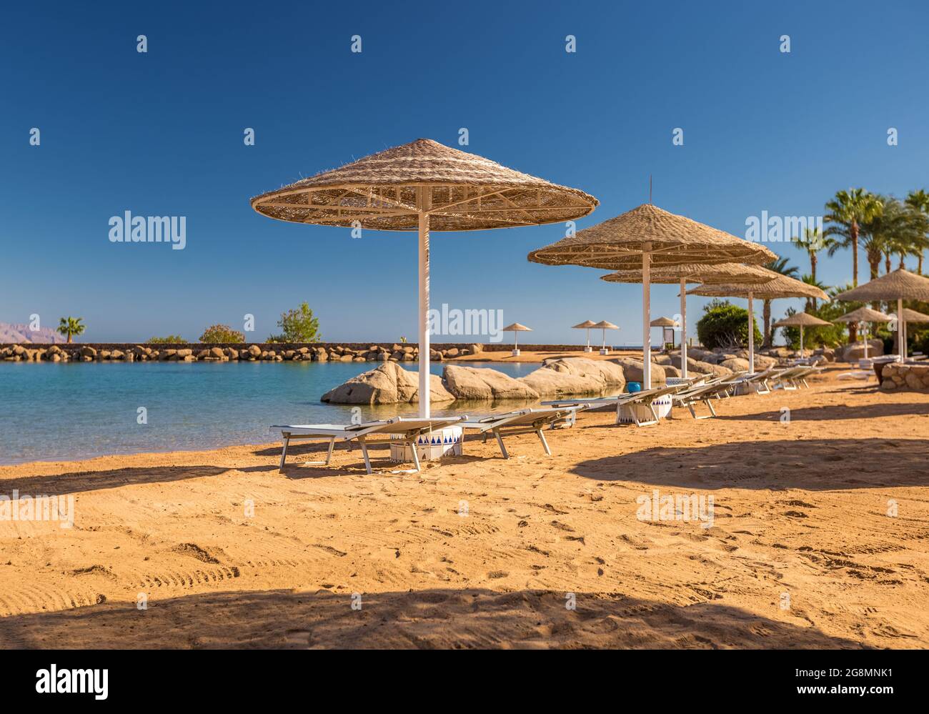 Straw umbrellas and sunbeds on the wonderful tropical beach. Stock Photo