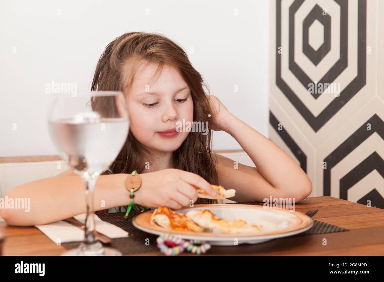 Little Caucasian girl has a lunch with Italian pizza Stock Photo