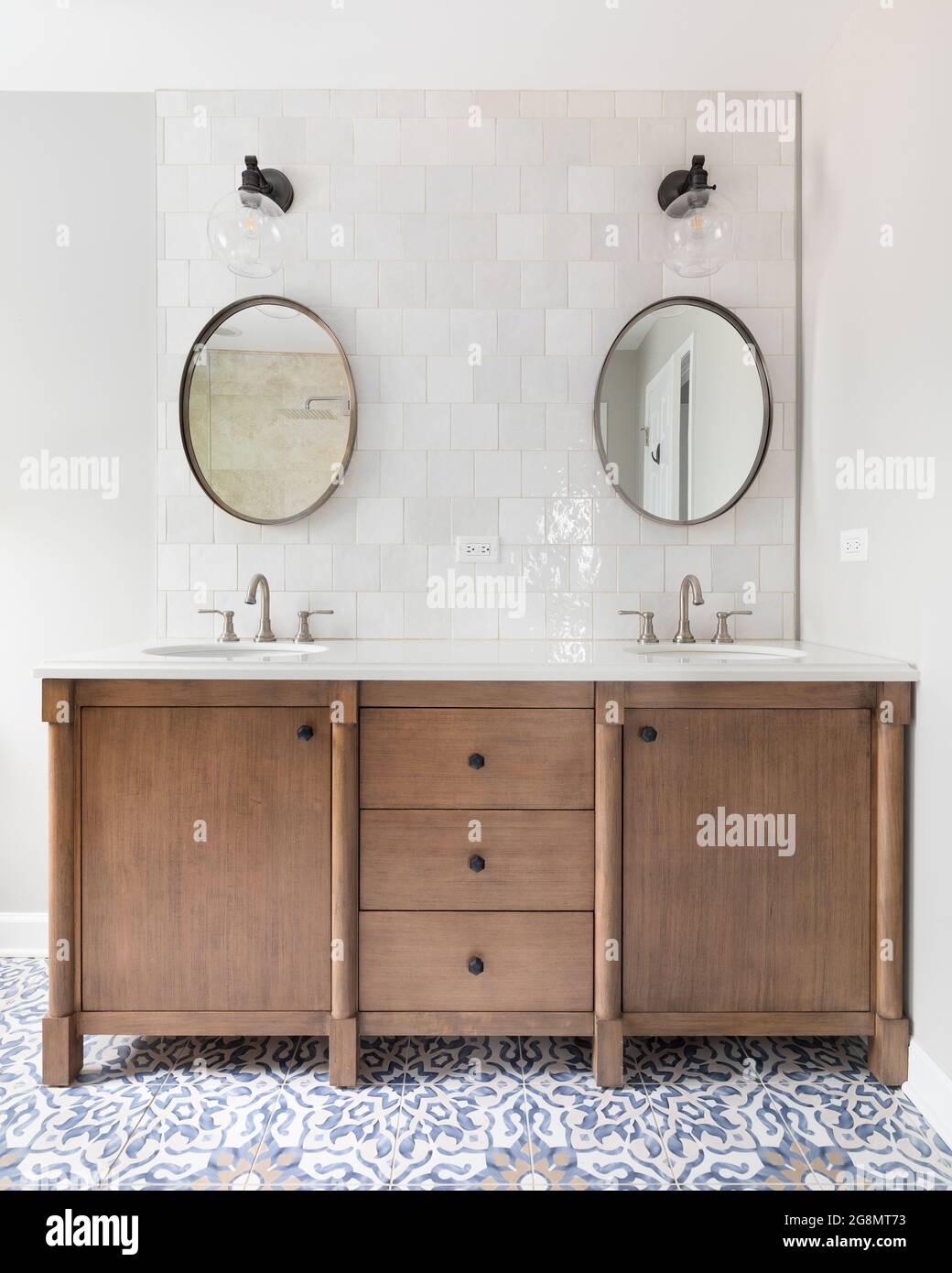 A cozy bathroom with a patterned tile floor, natural wood vanity, tiled